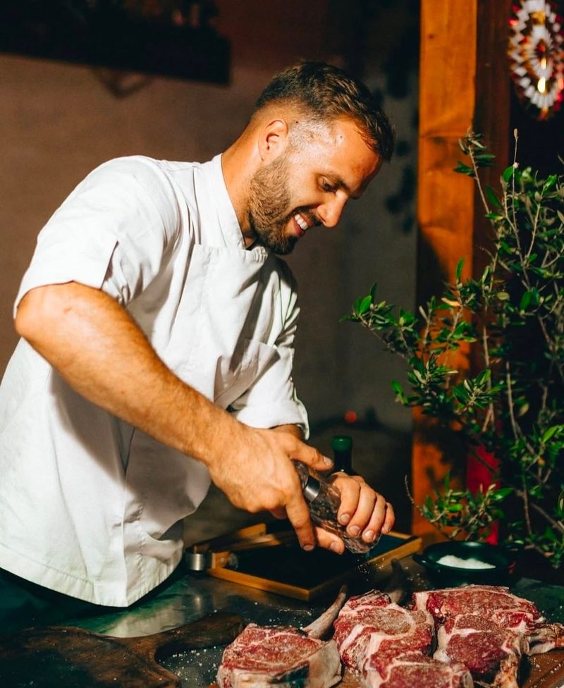 Chef Enrico Krluk seasoning dry-aged steaks at the pass in the Capri kitchen.