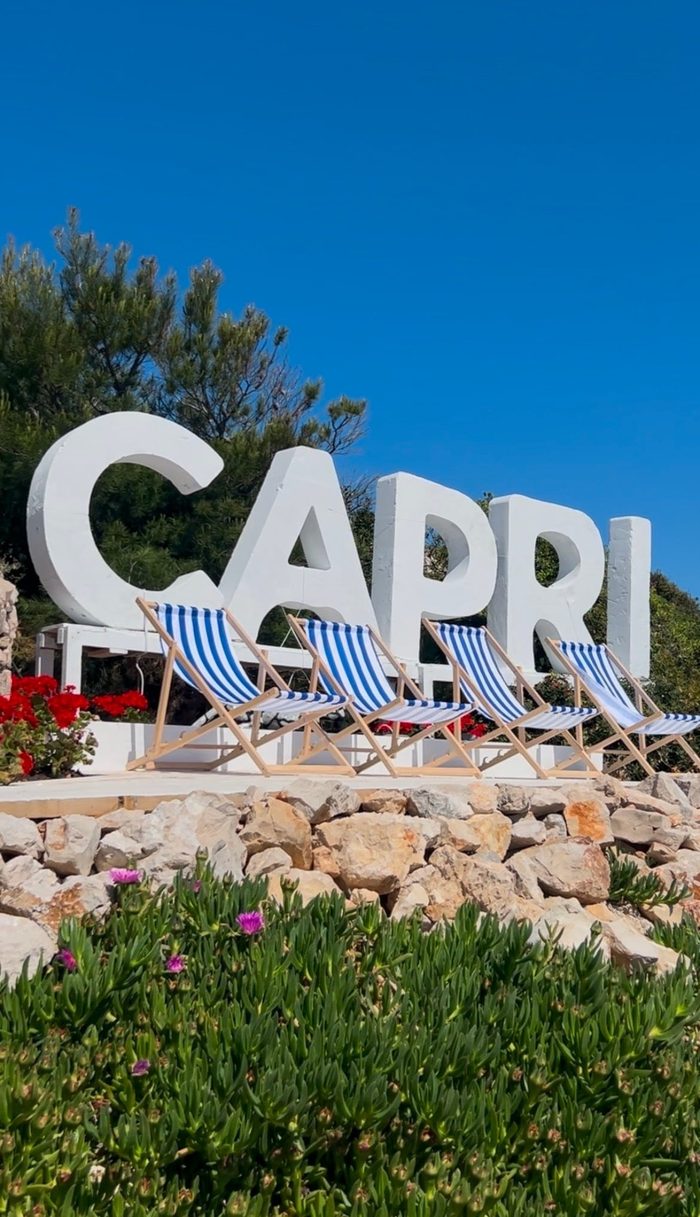 The white CAPRI letters on Kaprije Island, with blue-and-white striped deck chairs lined up in front of them.
